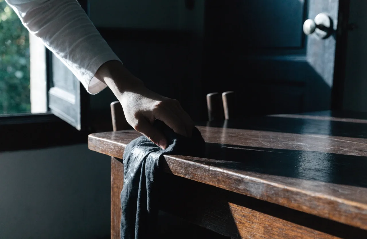 Tangan mengelap meja makan dan gagang pintu dengan kain pada pagi hari